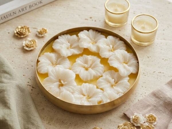 Round gold metal urli platter filled with wax and carved white hibiscus floral blooms with gold centers