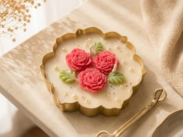 Scalloped urli candle filled with cream wax, pink peony flowers, pearls, and gold leaf flakes